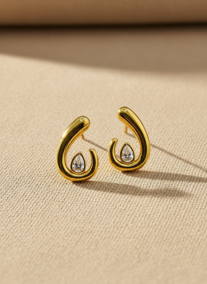 Gold earrings with gemstones on a beige fabric background