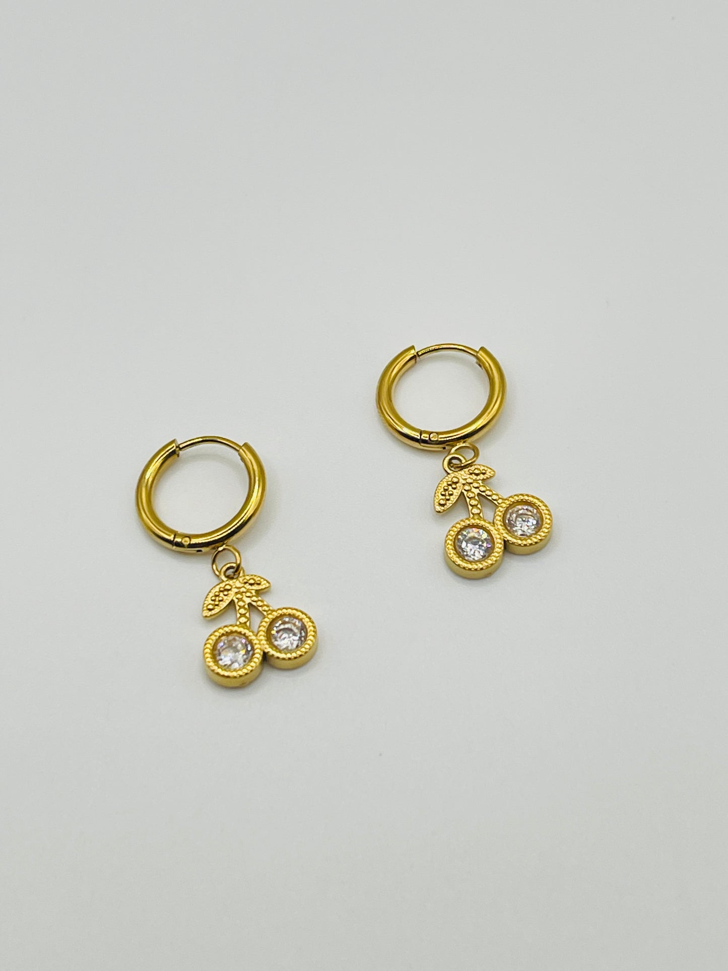 Gold hoop earrings with bicycle charm on a light gray background