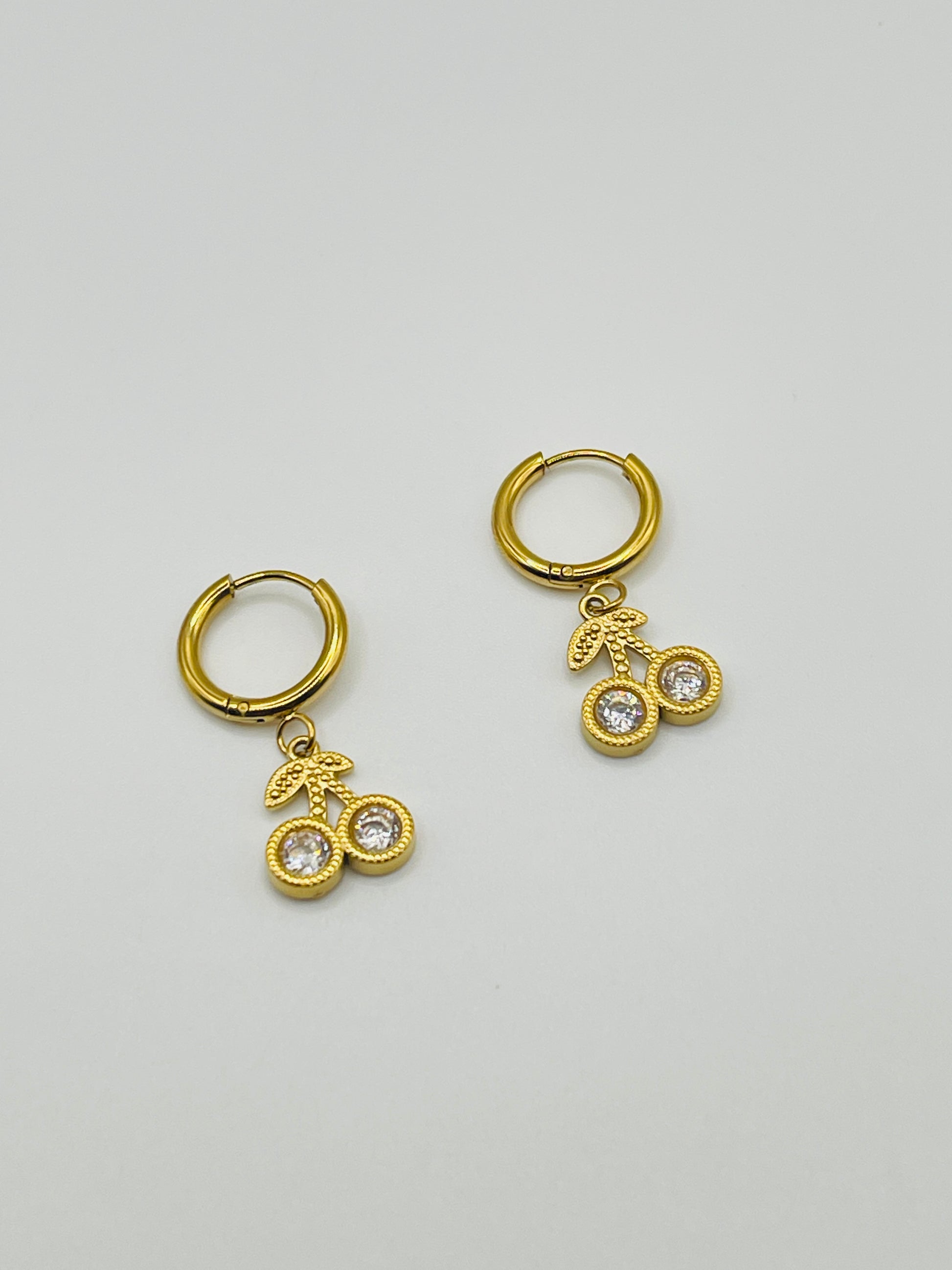 Gold hoop earrings with bicycle charm on a light gray background
