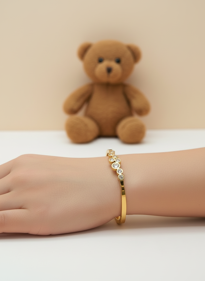 Gold bracelet with embedded stones on a light background