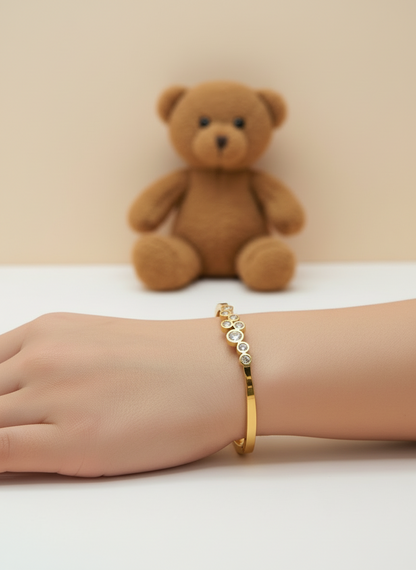 Gold bracelet with embedded stones on a light background