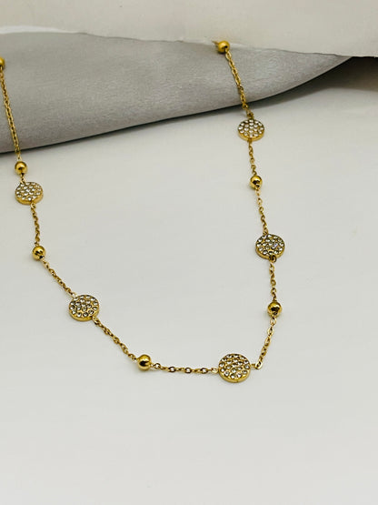 Gold necklace with decorative beads on a light gray surface