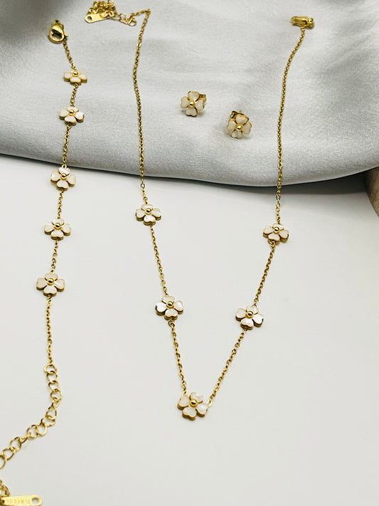 Gold necklace and earrings on a light gray surface