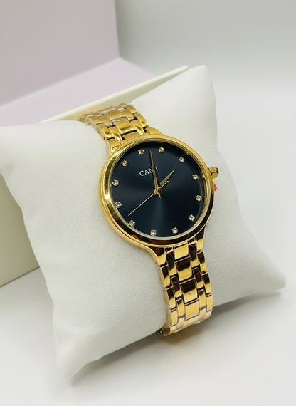 Gold wristwatch with black dial on a white cushion, brand visible