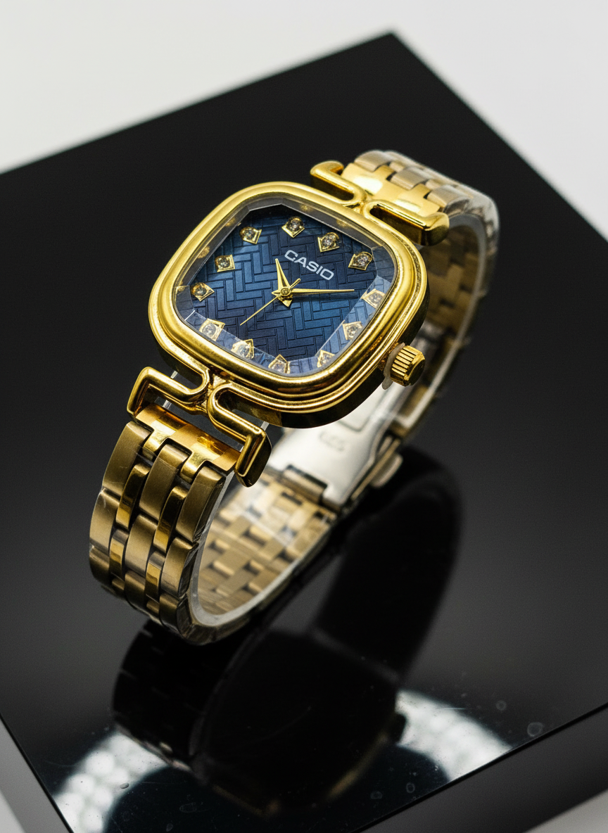 Gold Casio watch with blue face on a reflective black surface