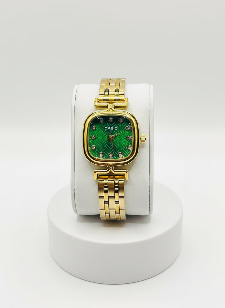 Gold Casio watch with green face on a white cushion