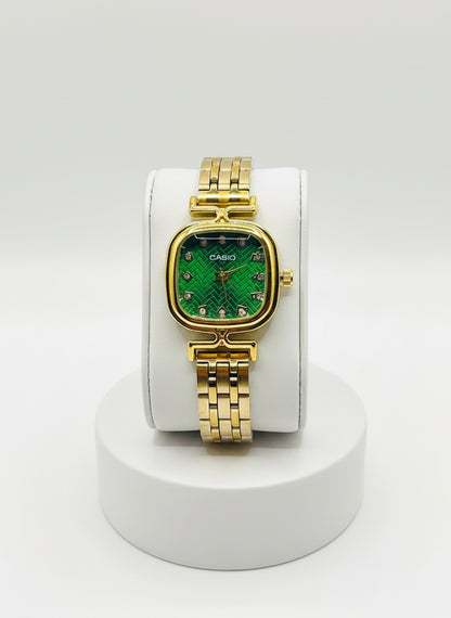 Gold Casio watch with green face on a white cushion