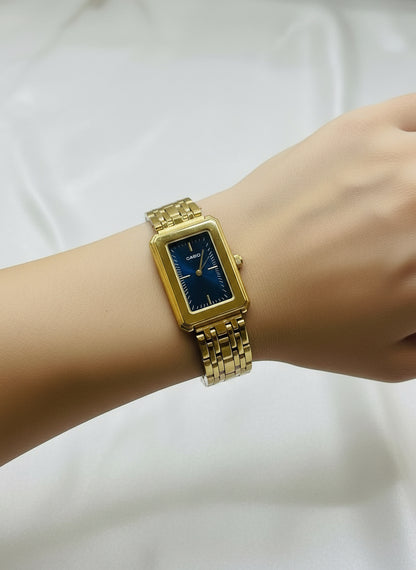 Gold Casio watch on a white cushion with a gray box in the background