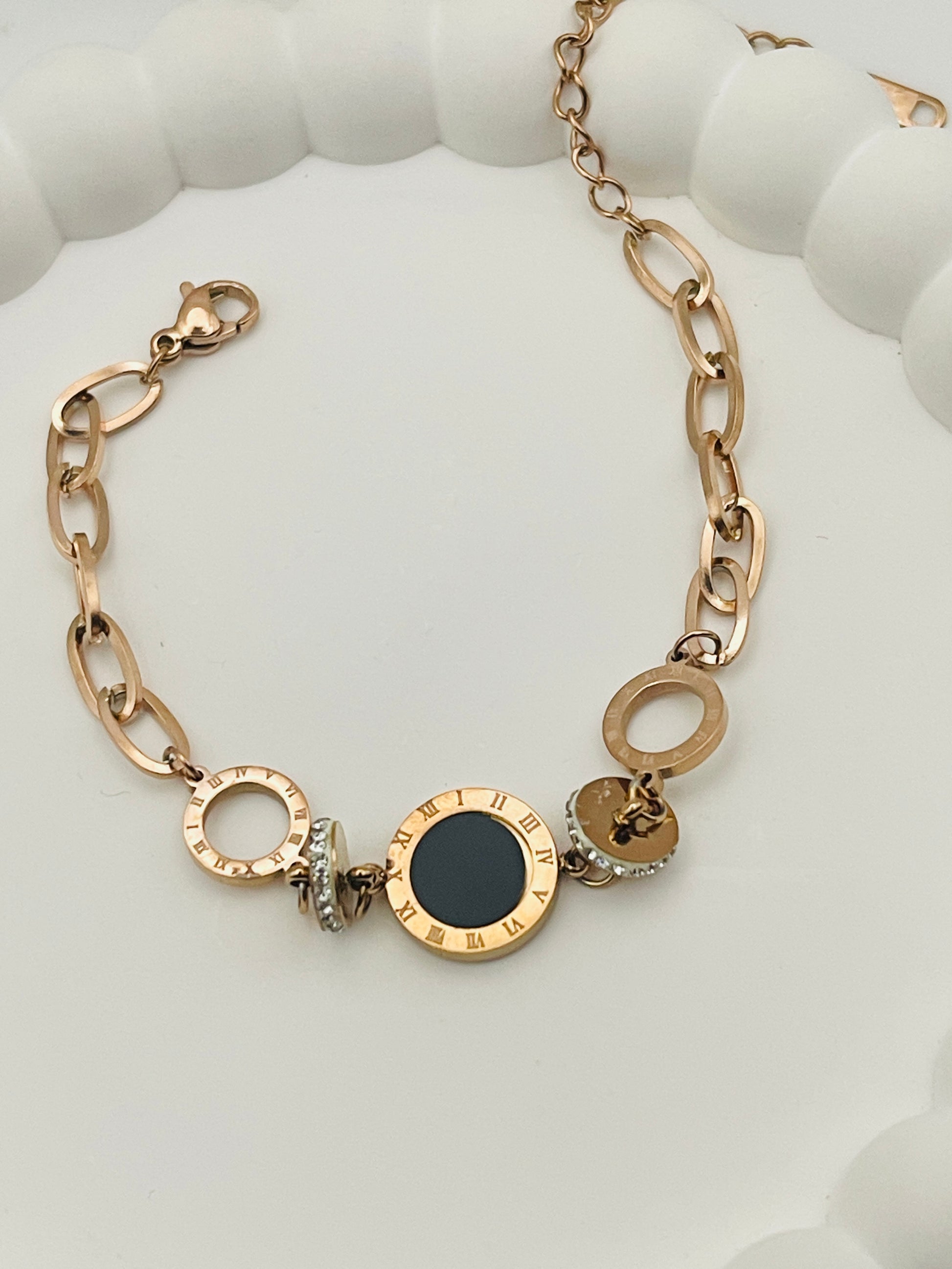 Rose Gold bracelet with black center and chain links on a white surface