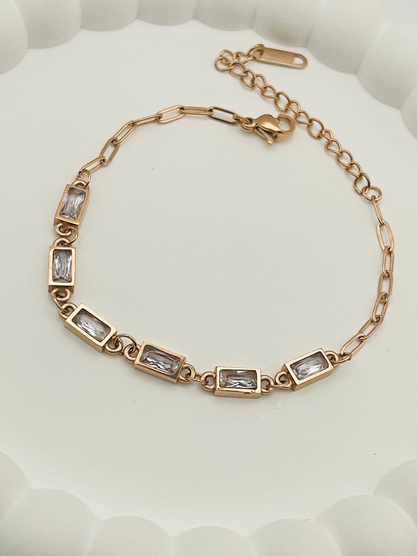 Rose Gold bracelet with embedded stones on a white textured background