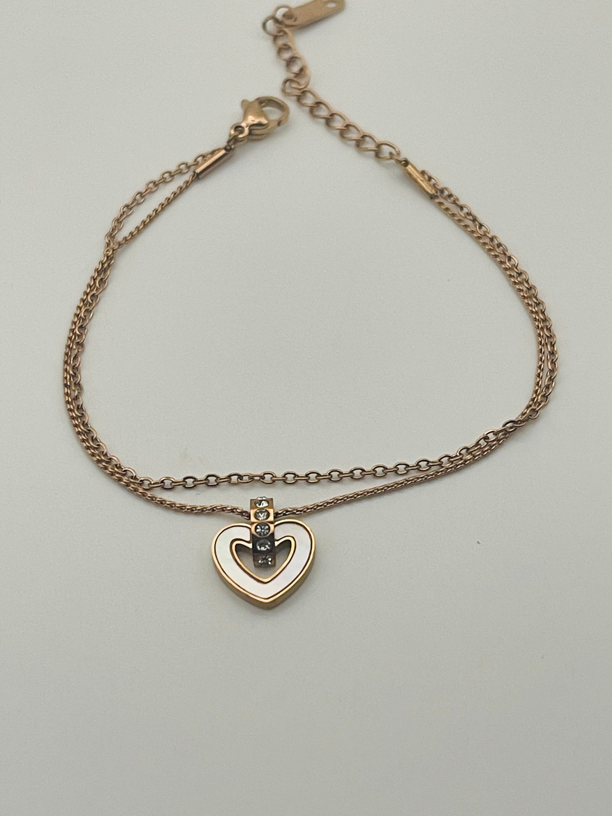 Rose Gold bracelet with a heart-shaped pendant on a light gray background