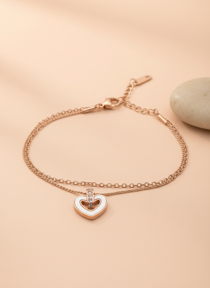 Rose gold bracelet with a heart-shaped charm on a beige background