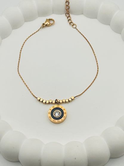 Rose Gold bracelet with a circular pendant on a white textured surface