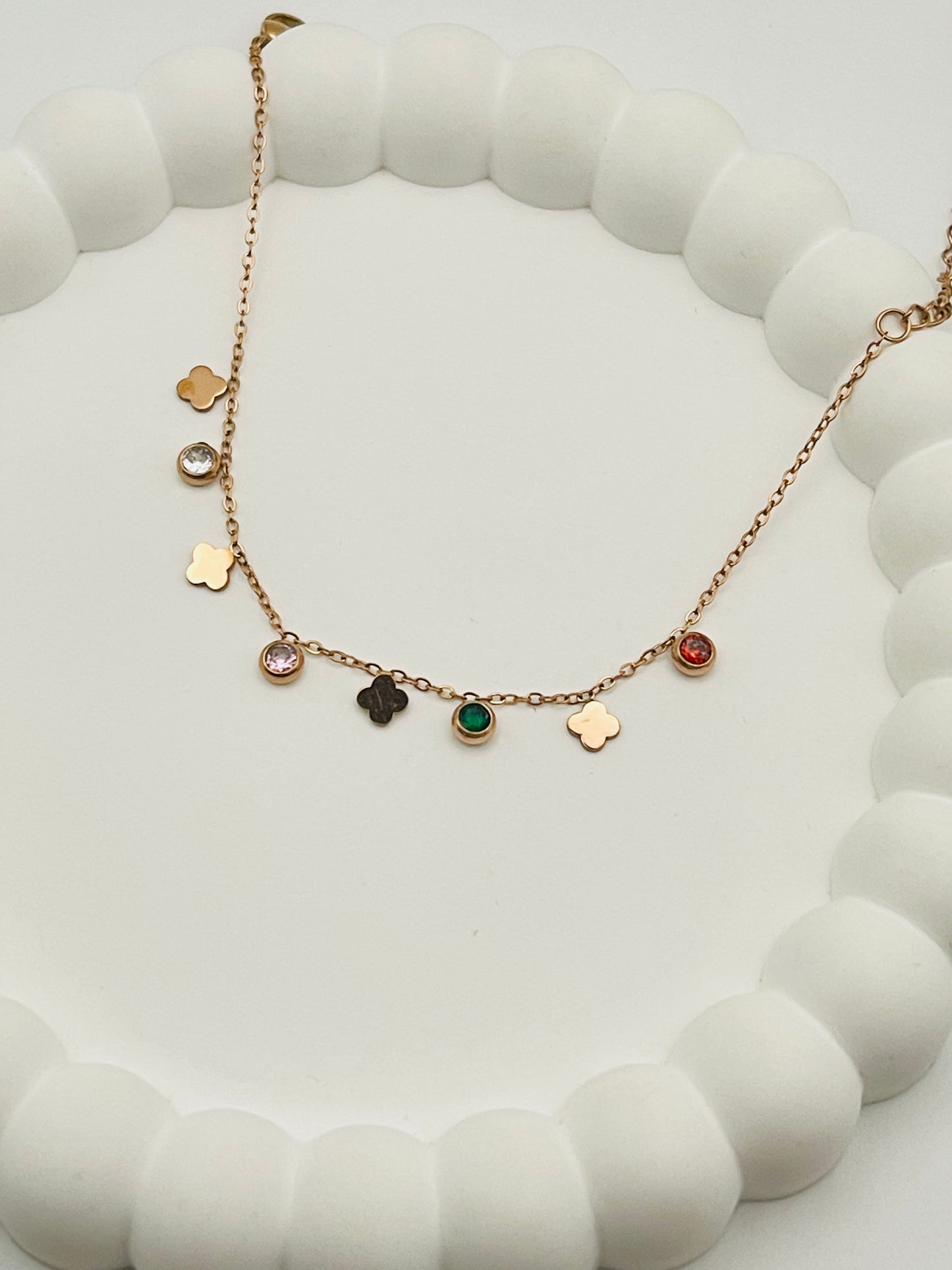 Rose gold bracelet with various charms on a white surface