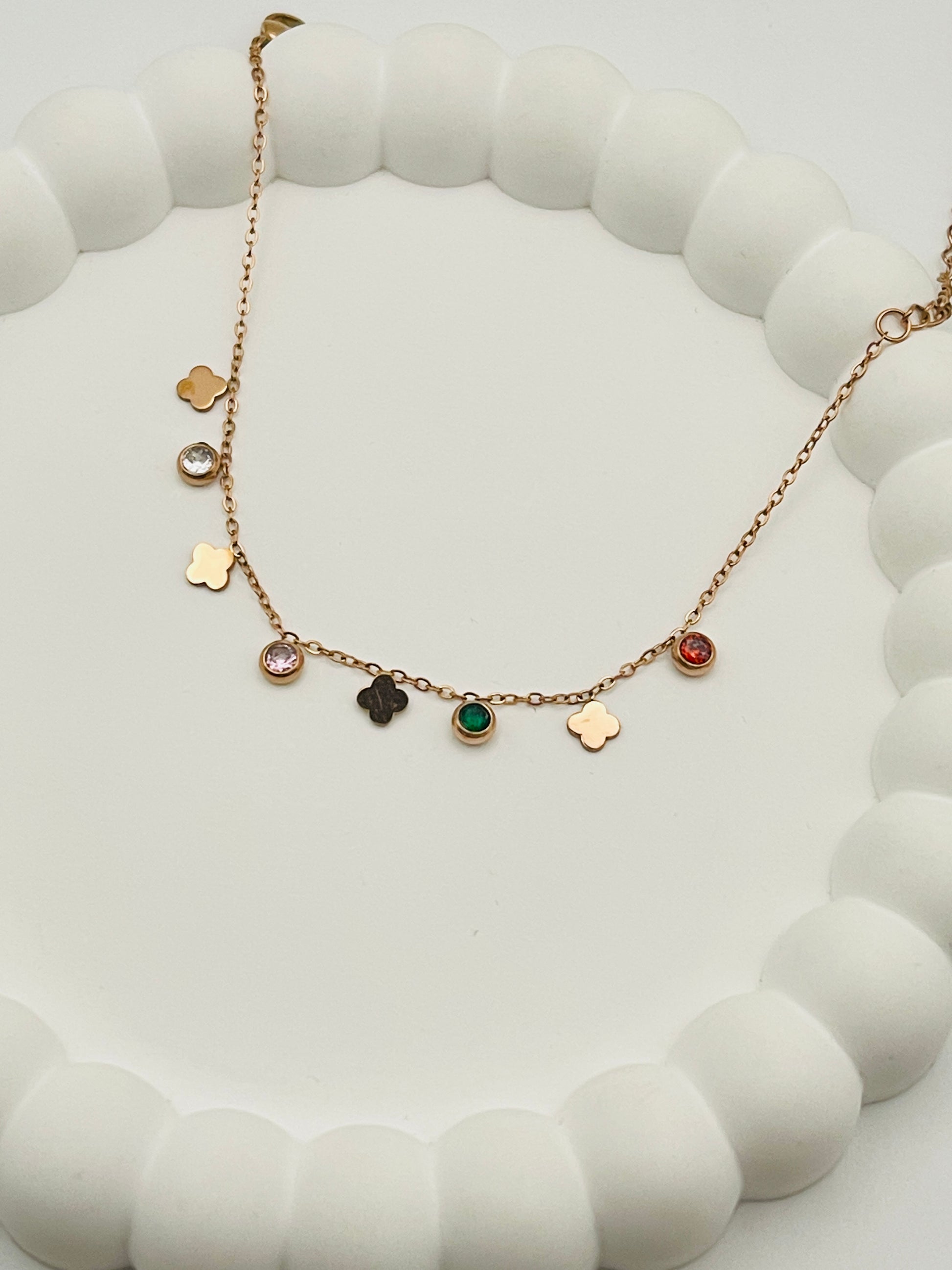 Rose gold bracelet with various charms on a white surface