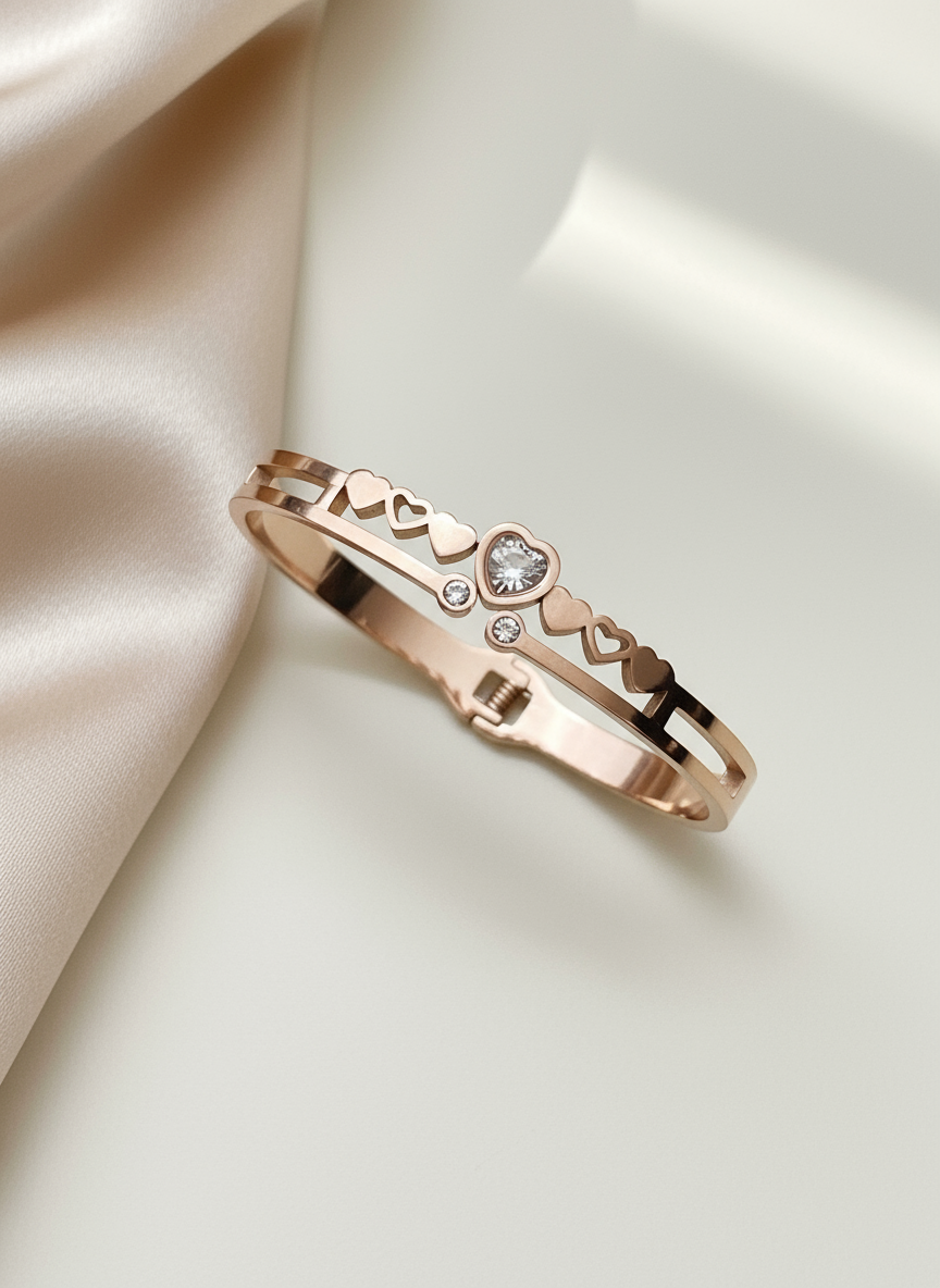 Rose gold bracelet with heart and diamond design on a satin surface