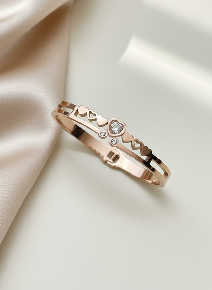 Rose gold bracelet with heart and diamond design on a satin surface