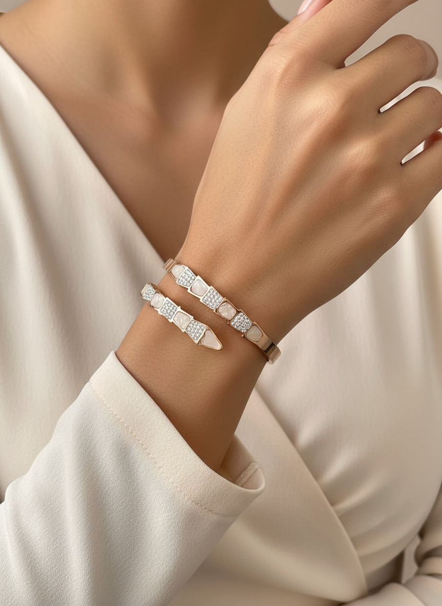 Close-up of a hand wearing two silver bracelets on a neutral background