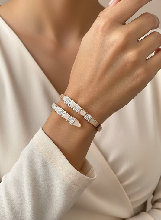Close-up of a hand wearing two silver bracelets on a neutral background