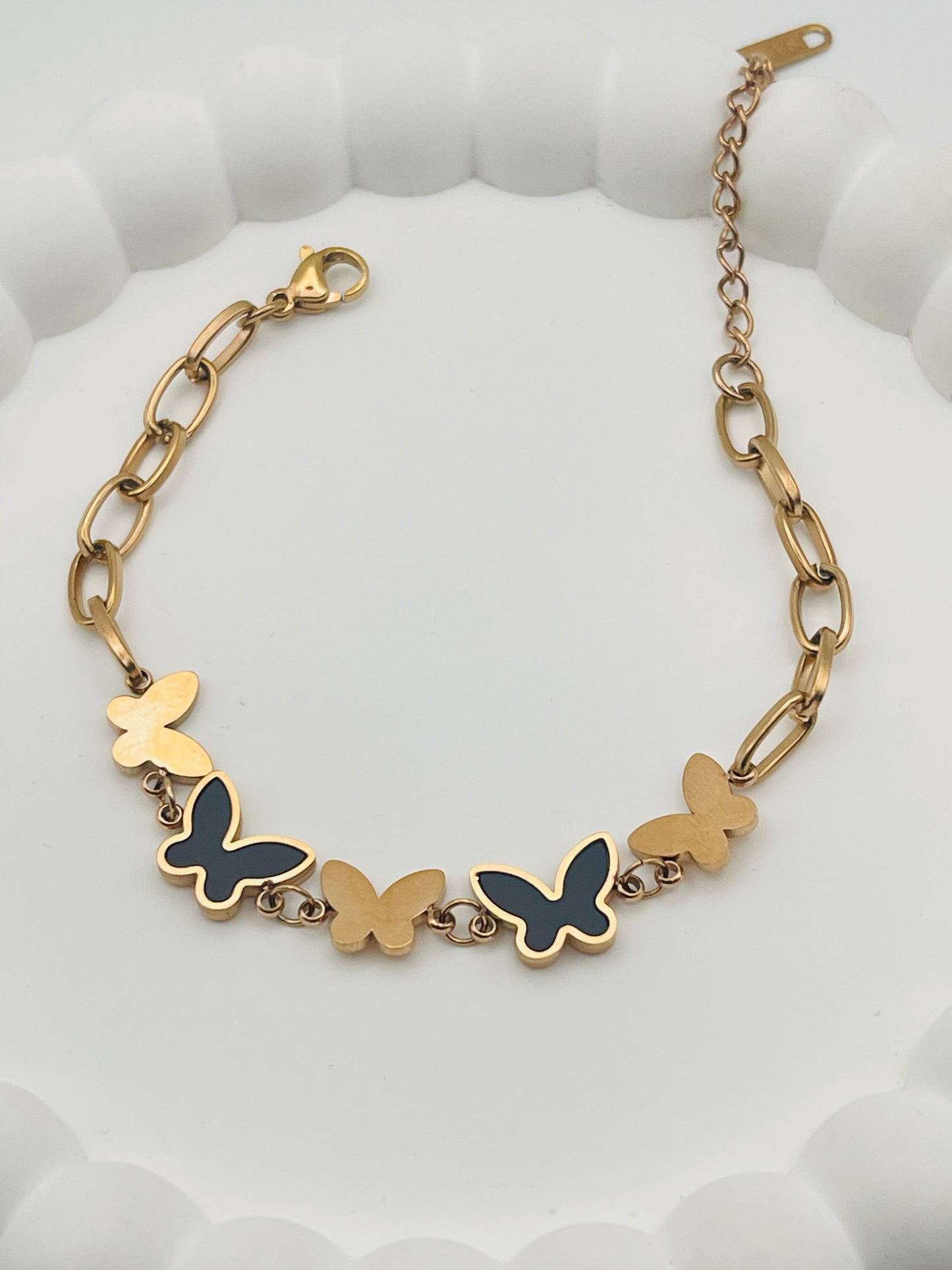 Rose Gold bracelet with butterfly charms on a white textured background