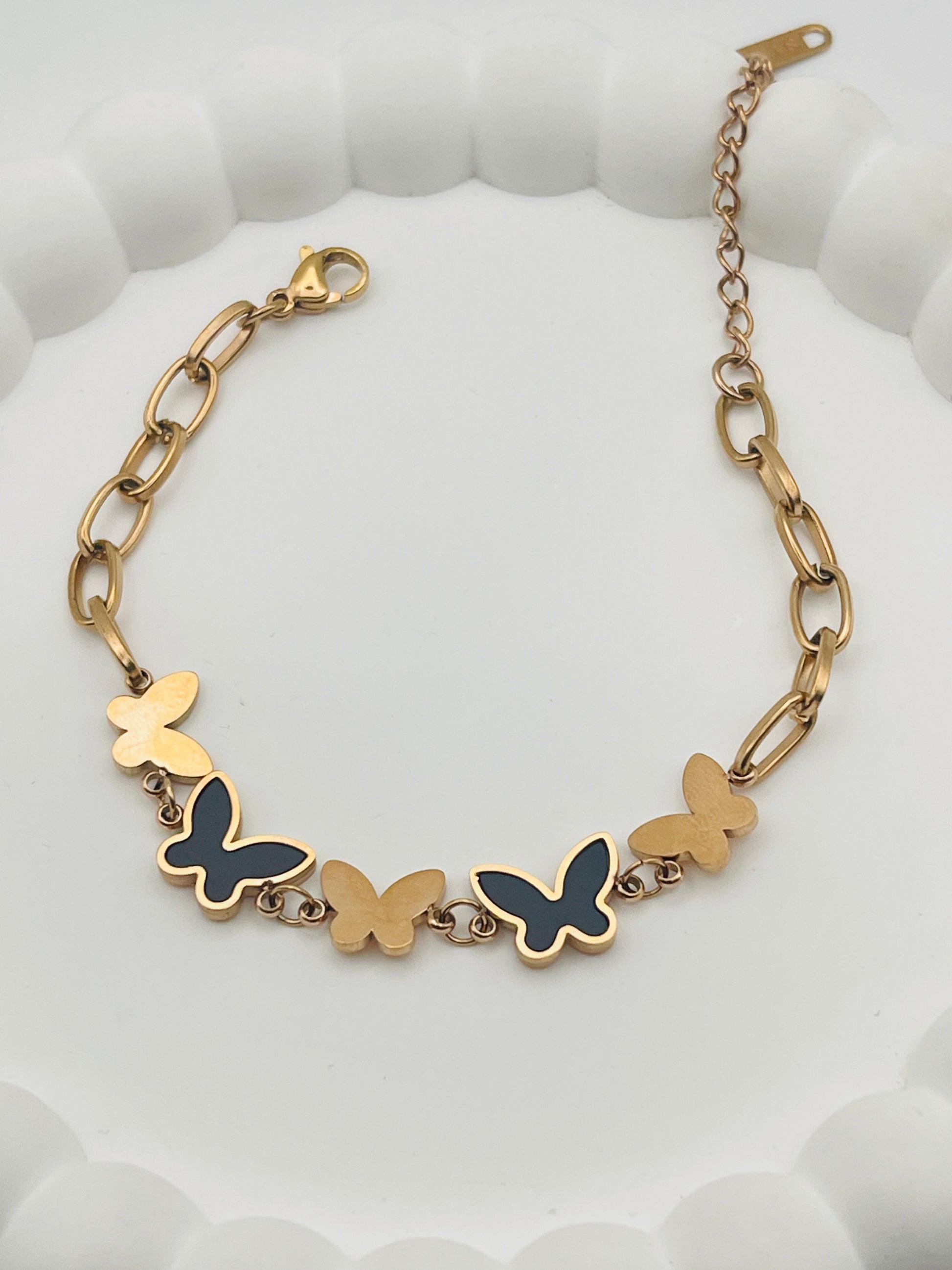 Rose Gold bracelet with butterfly charms on a white textured background