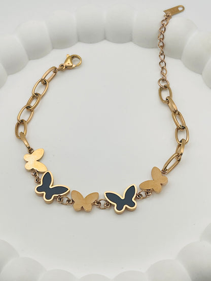 Rose Gold bracelet with butterfly charms on a white textured background