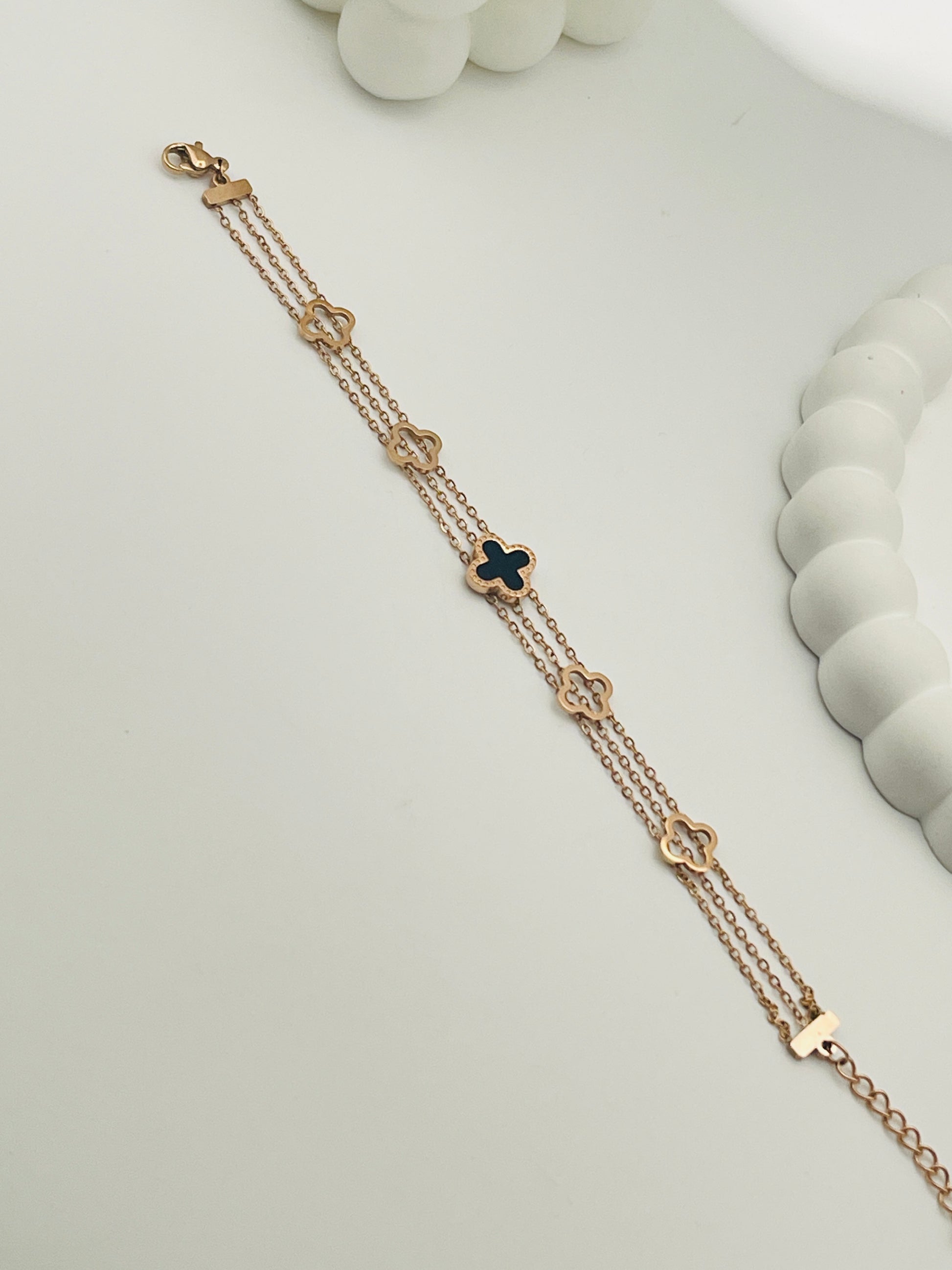 Rose Gold bracelet with clover-shaped charms on a light gray background