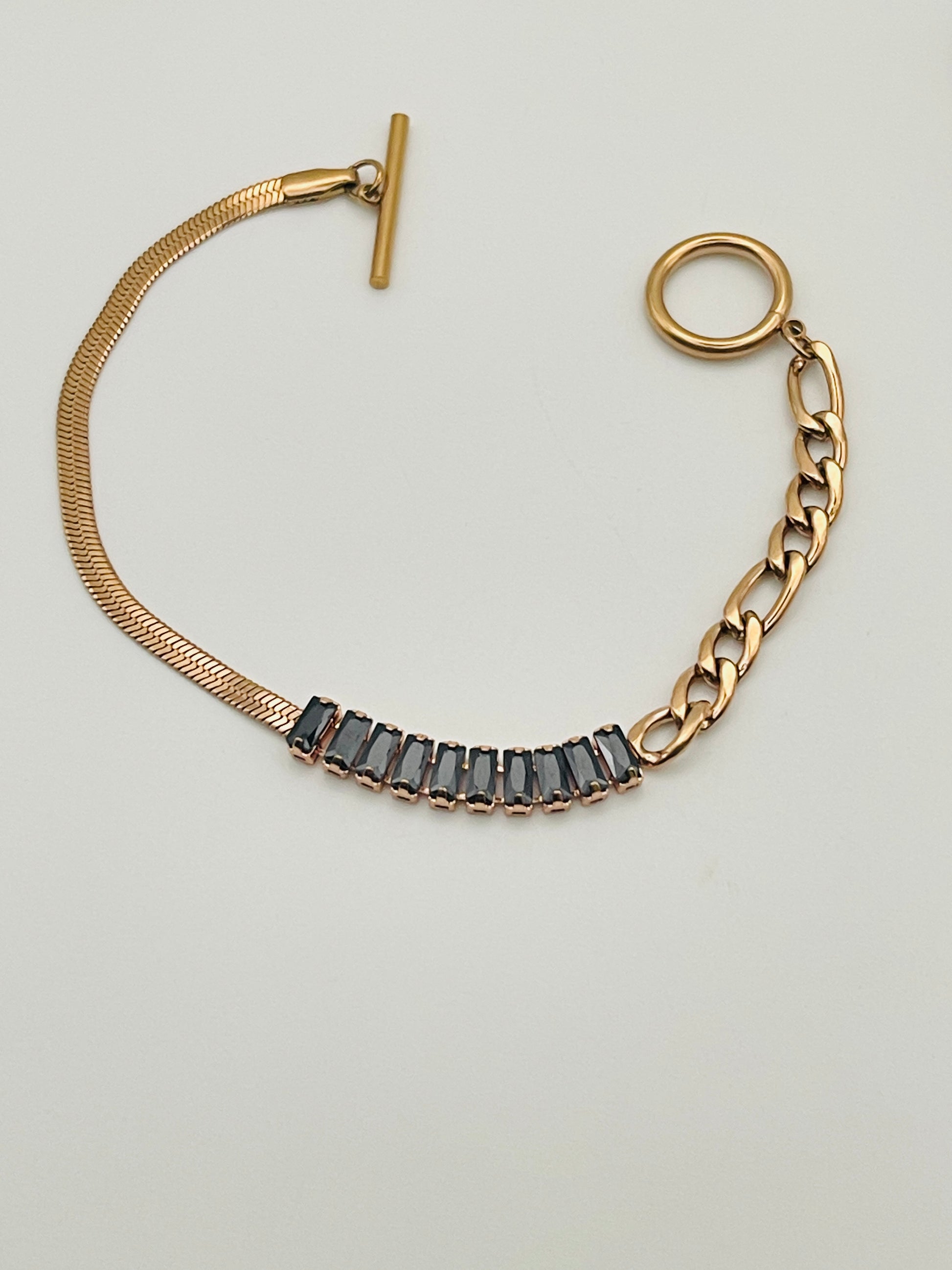 Rose Gold bracelet with black gemstones on a light gray background
