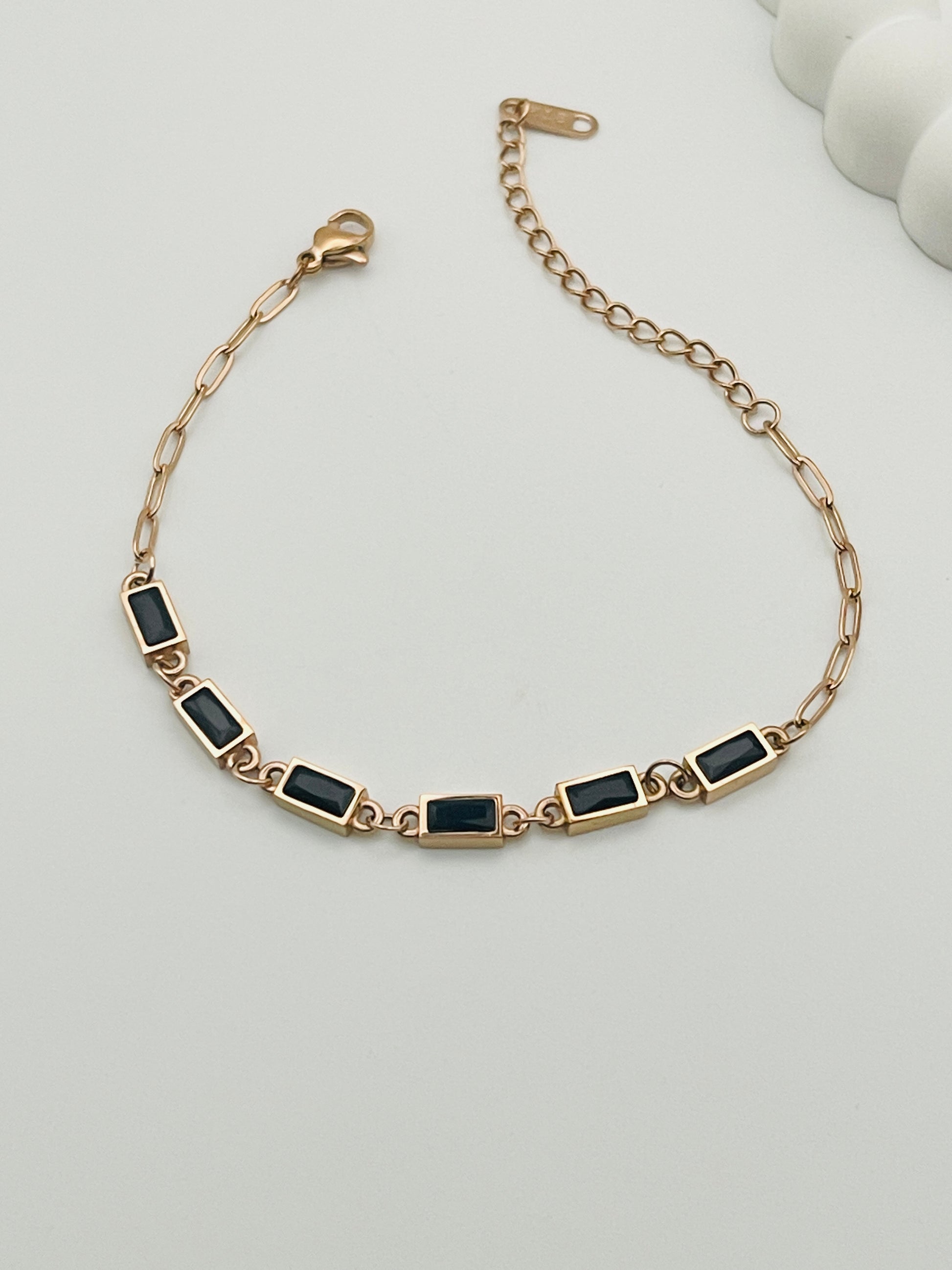 Rose Gold bracelet with black stones on a light gray background