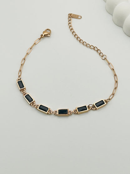 Rose Gold bracelet with black stones on a light gray background