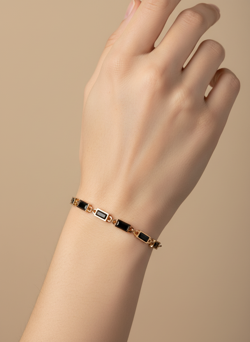 Gold bracelet with black stones on a light gray background