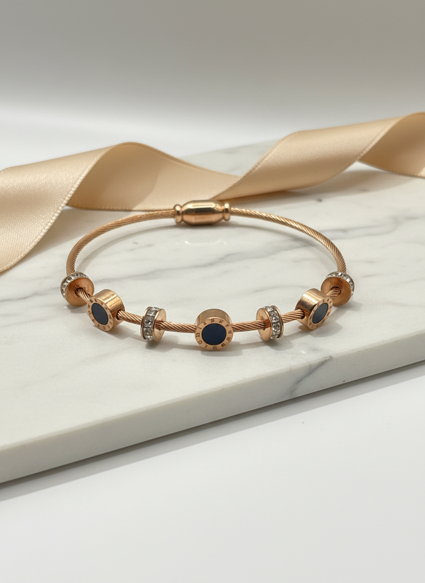 Rose gold bracelet with blue stones on a white surface with a beige ribbon