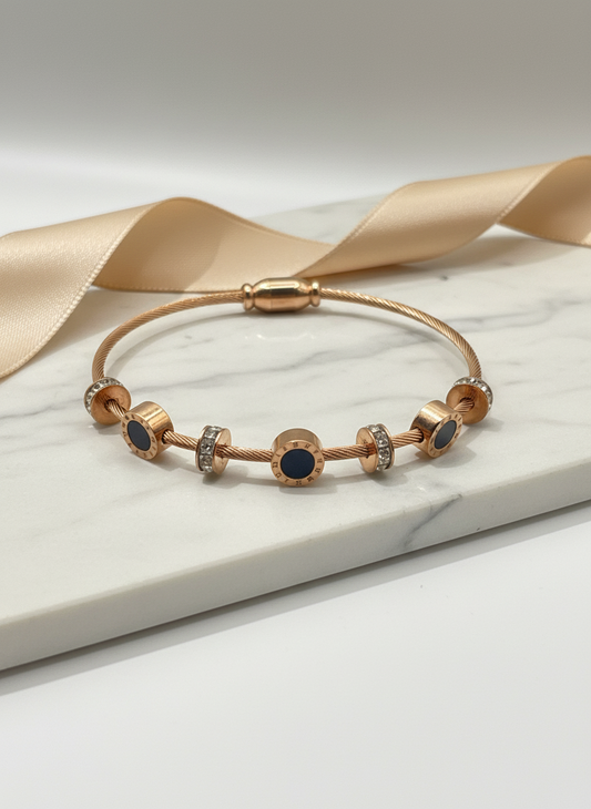 Rose gold bracelet with blue stones on a white surface with a beige ribbon