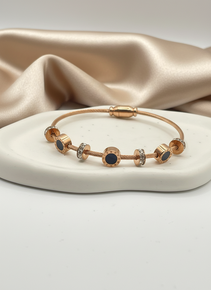 Rose Gold bracelet with blue stones on a white dish with beige fabric background