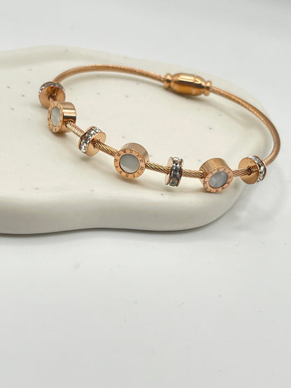Gold bracelet with circular links on a white stone surface