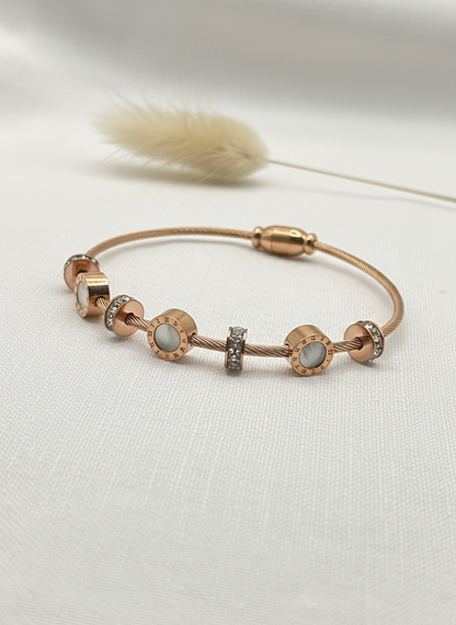 Rose gold bracelet with gemstones on a light background