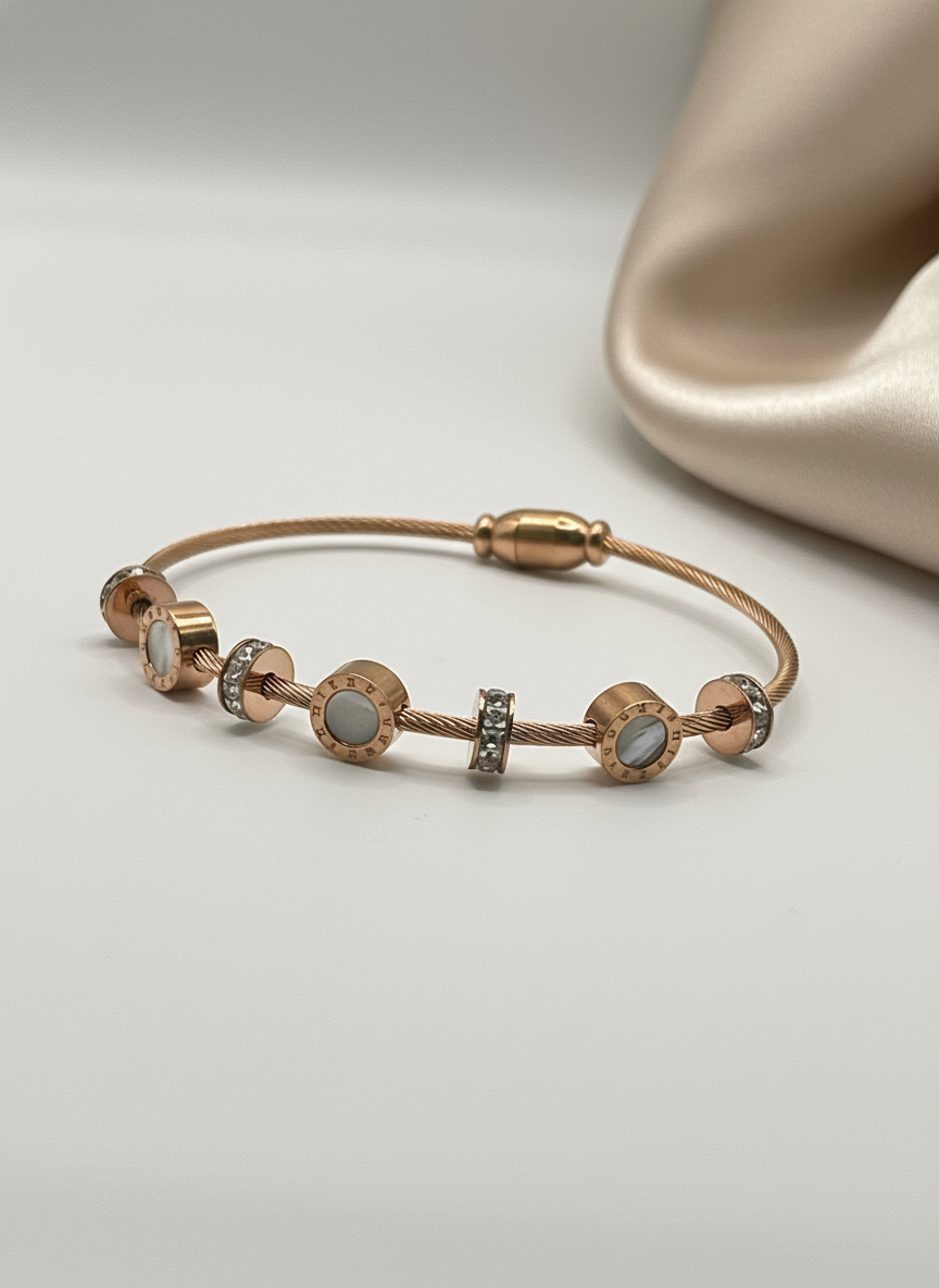 Rose gold bracelet with gemstones on a light gray background