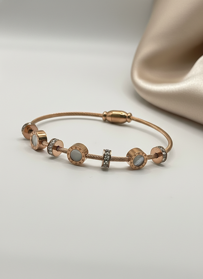 Rose gold bracelet with gemstones on a light gray background
