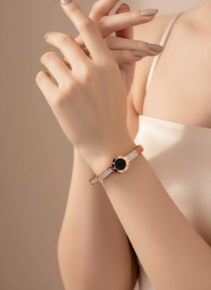 Rose gold bracelet with black gemstone on a wrist against a beige background