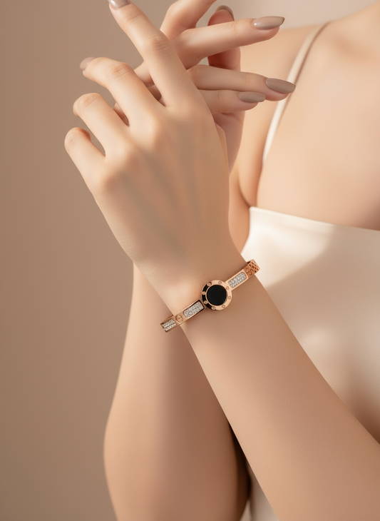Rose gold bracelet with black gemstone on a wrist against a beige background