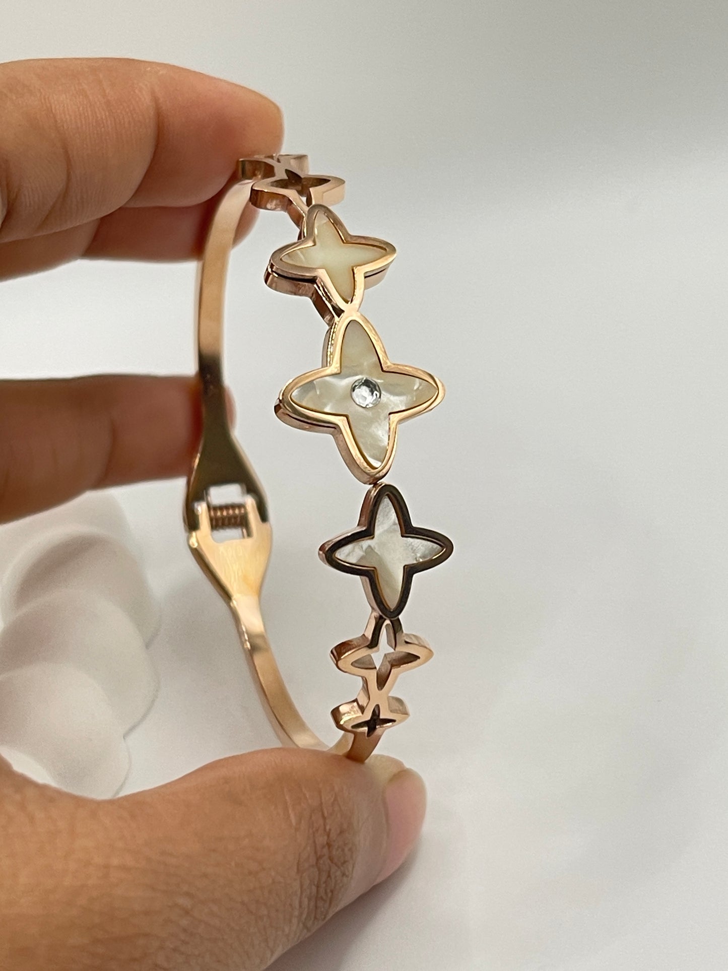 Rose Gold bracelet with star and circle designs held by a hand against a light background
