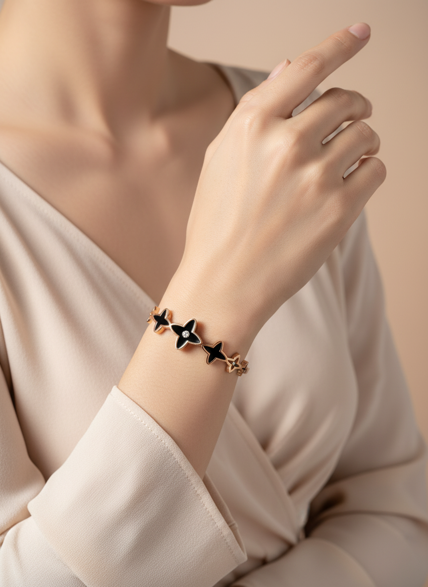 Close-up of a hand wearing a bracelet with star-shaped charms on a neutral background