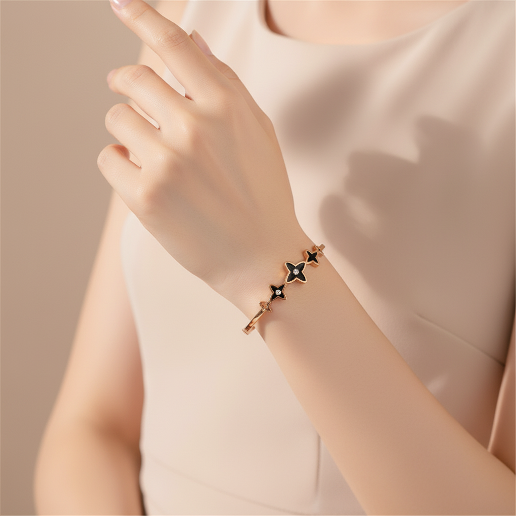 Hand wearing a delicate bracelet with star-shaped charms against a neutral background