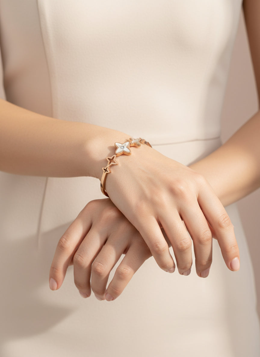 Rose gold bracelet with star designs on a light gray background