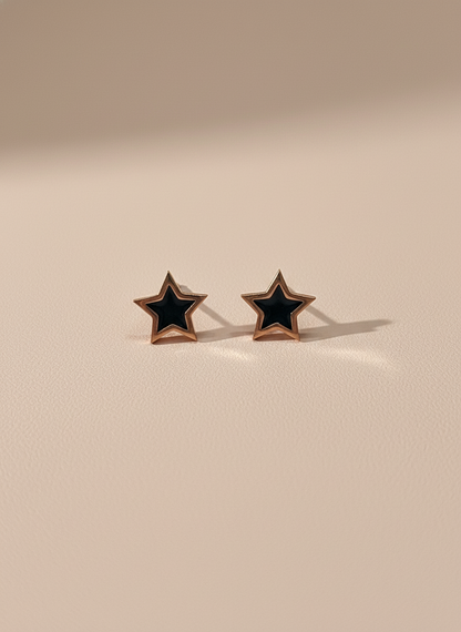 Star-shaped rose gold stud earrings with black centers on a beige background