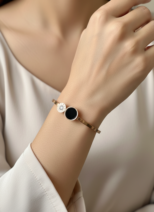 Close-up of a wrist wearing a bracelet with a black stone and silver accents on a neutral background.