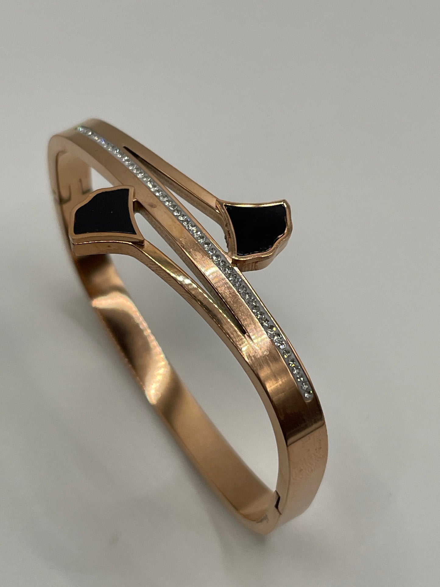 Rose gold bracelet with black accents on a light gray background