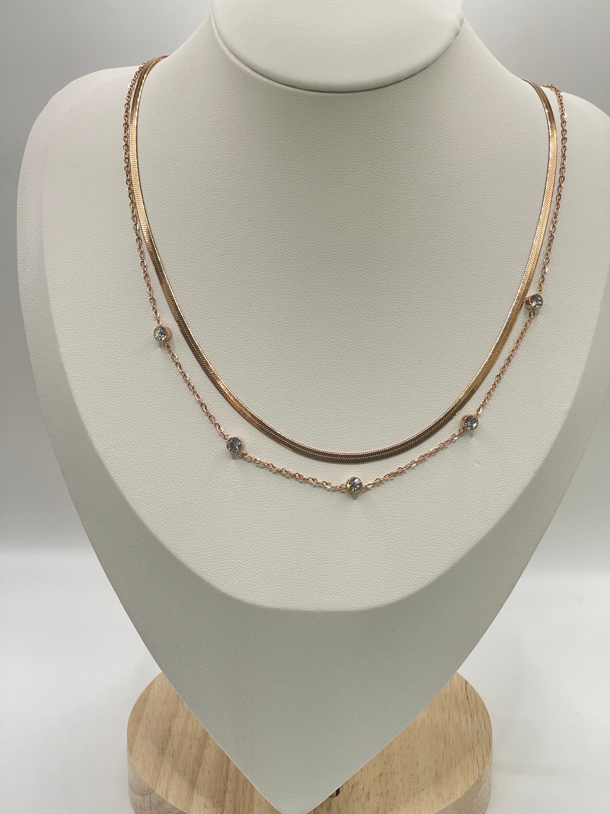 Delicate rose gold double layer necklace on a mannequin bust against a neutral background
