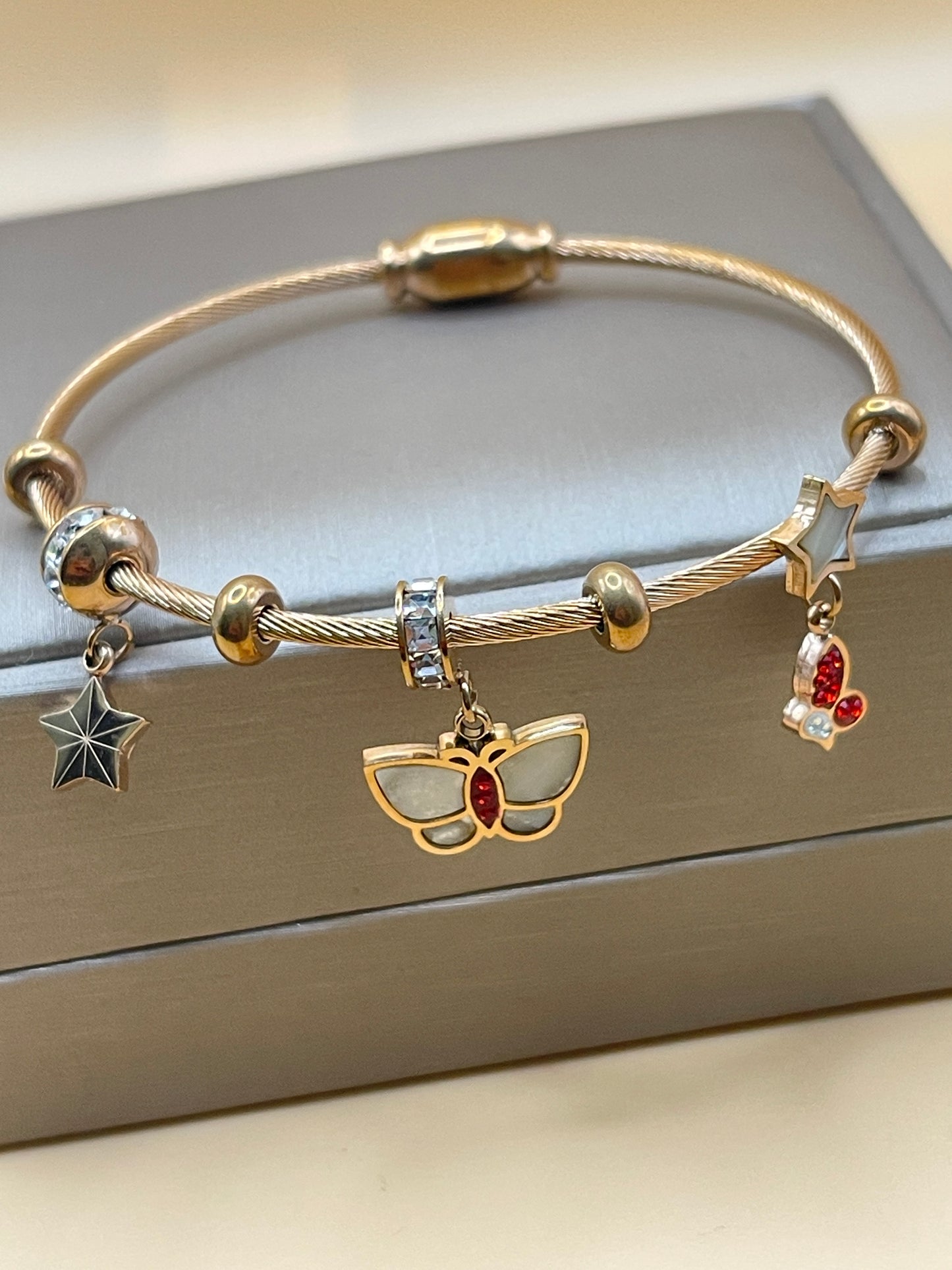 Rose Gold bracelet with charms on a neutral background