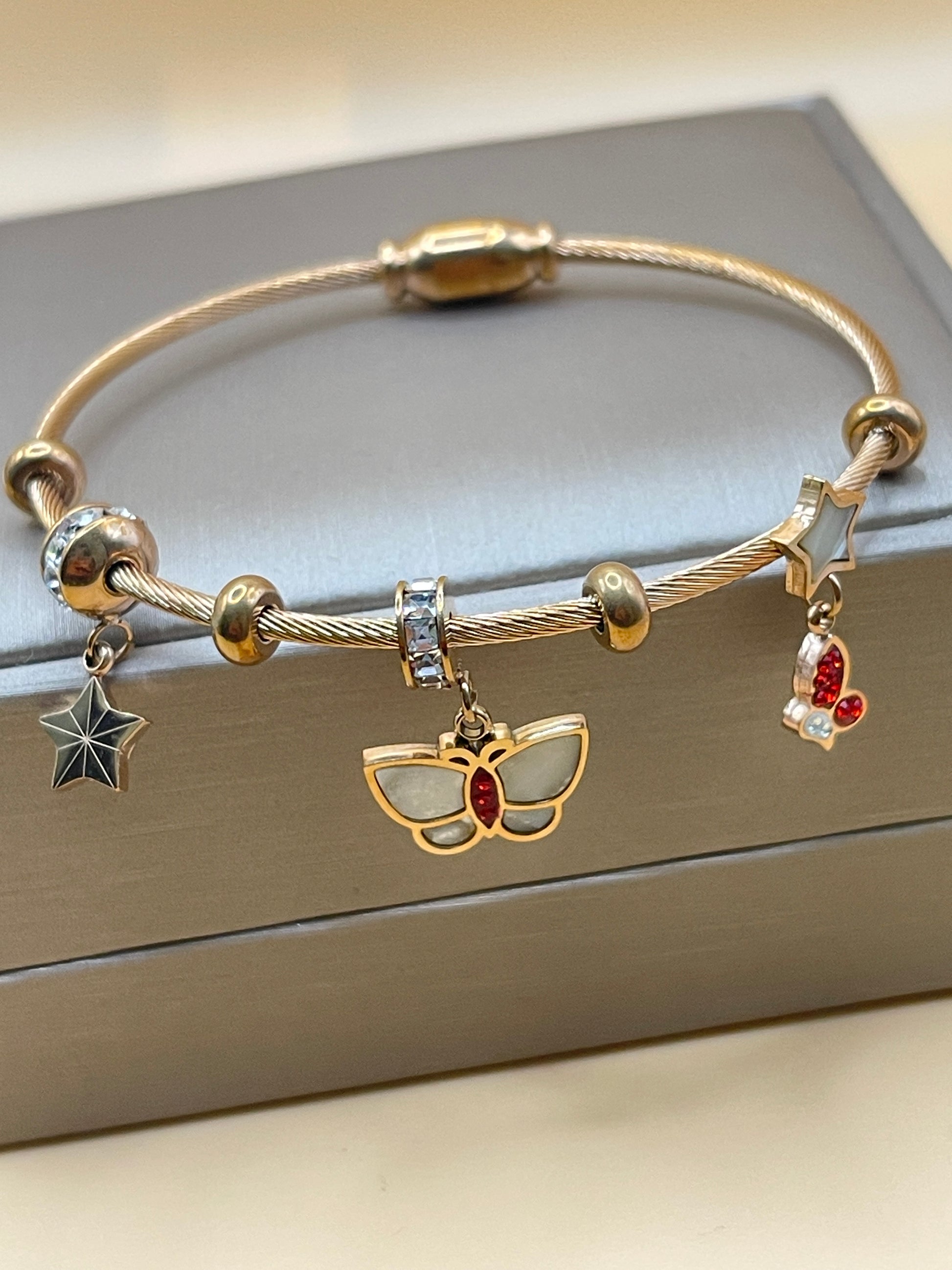 Rose Gold bracelet with charms on a neutral background